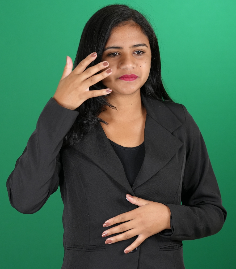 Intérprete faz um sinal em Libras diante de um fundo verde